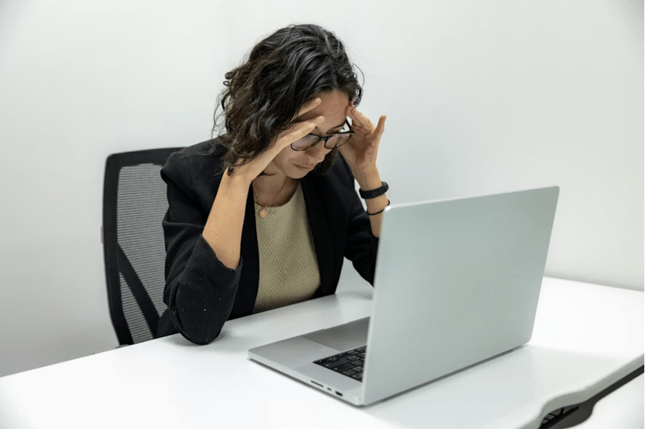 Dirigeante d'entreprise anxieuse se tenant la tête face à son écran d'ordinateur.