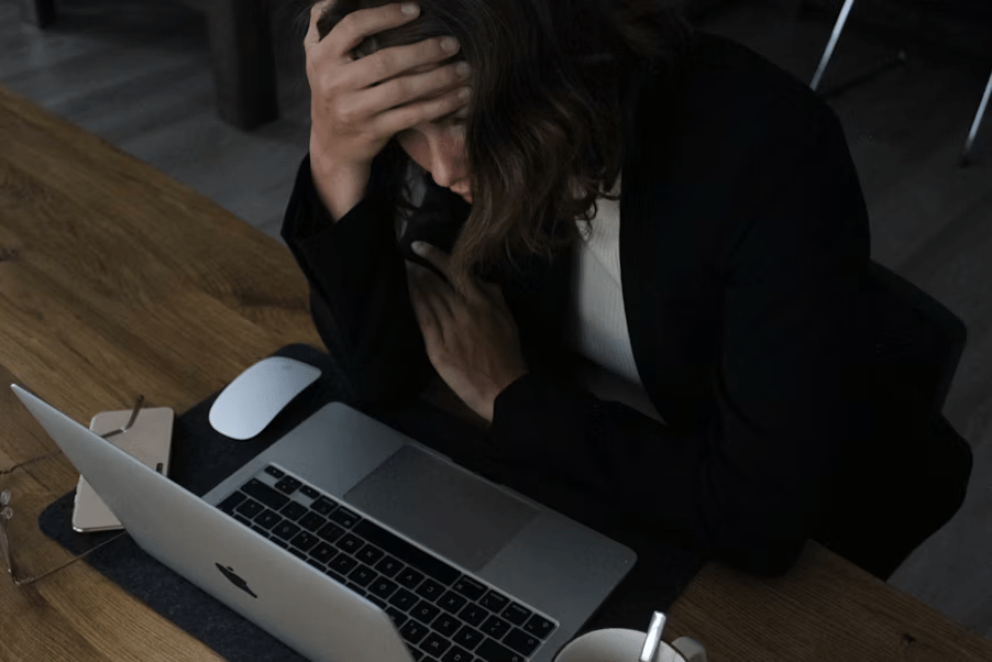 Femme entrepreneure fatiguée et stressée se tenant la tête devant son ordinateur portable.