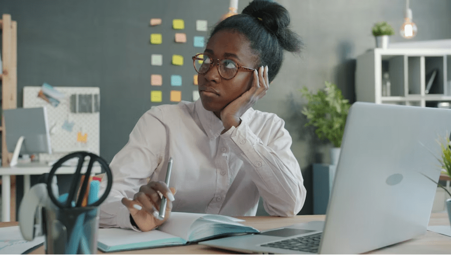 Femme entrepreneure pensive assise à son bureau devant son ordinateur portable, face à une baisse d'activité.