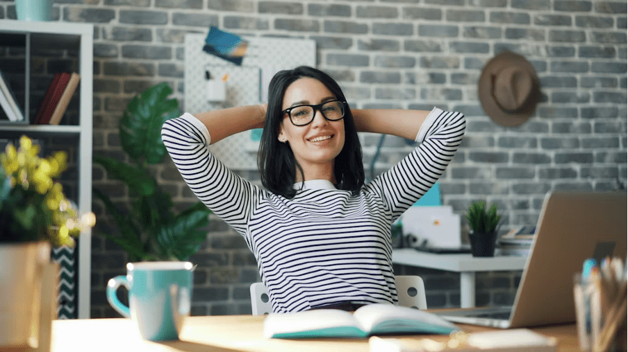 Femme dirigeante détendue et souriante, les mains derrière la tête, ayant terminé sa journée de travail.