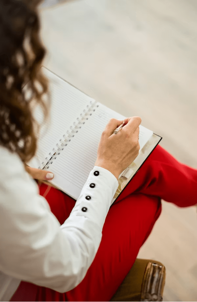 Dirigeante écrivant ses victoires professionnelles dans un carnet pour contrer le biais de négativité.